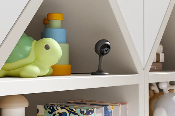 The smart Hama indoor surveillance camera with Wi-Fi, night vision, motion sensor and 1080p resolution is also located on a shelf where children's toys are stored 